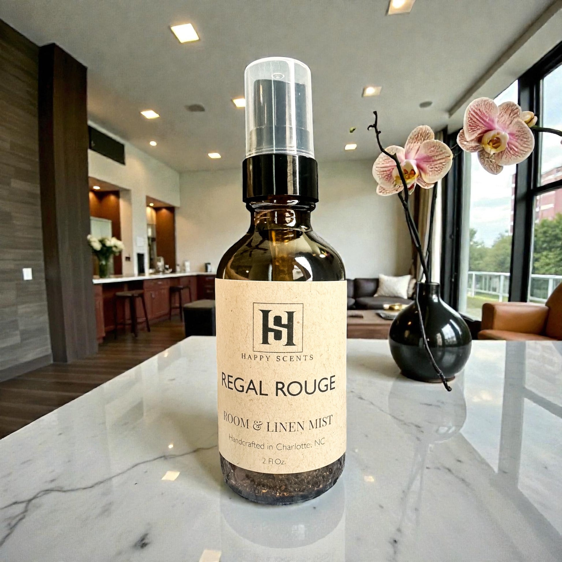 Bottle of Happy Scents Regal Rouge room and linen mist on a marble countertop with a modern interior background.