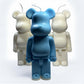 Blue bear-shaped candle with two white bear-shaped candles on a white background