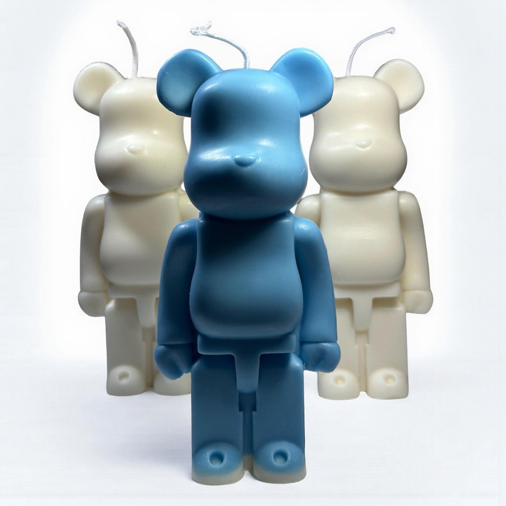 Blue bear-shaped candle with two white bear-shaped candles on a white background