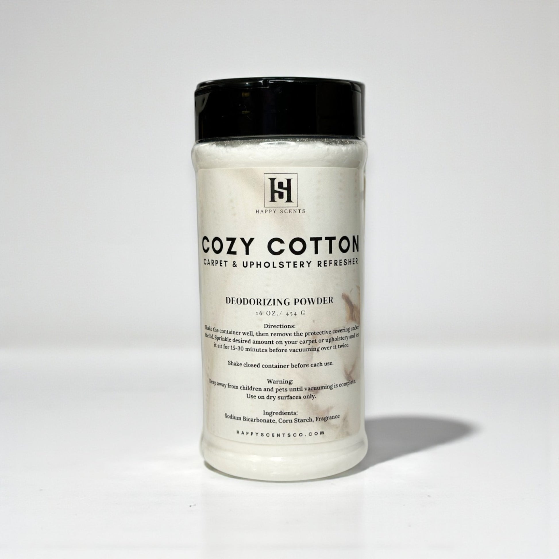 Plastic Clear Cylindrical Container of 'Cozy Cotton' deodorizing powder with a black lid on a white background